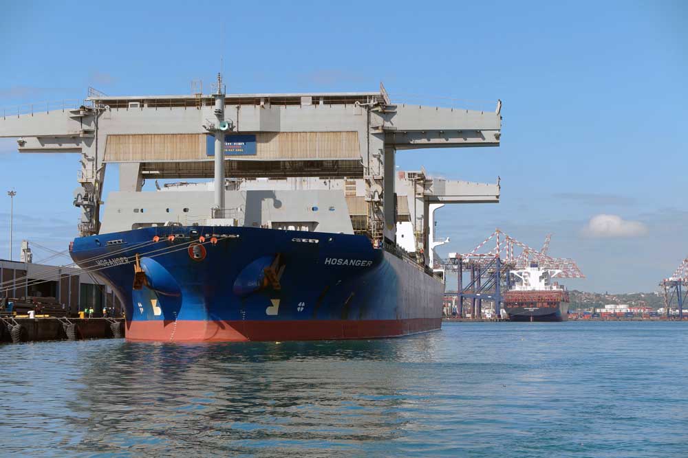 Large cargo vessel Hosanger docked at Durban harbour showing industrial port cranes and shipping operations