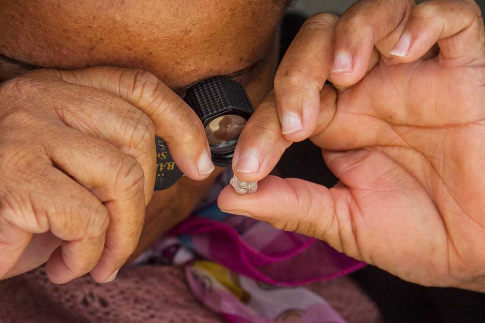 Female diamond inspector in Botswana examining gemstone through microscope showing precision quality assessment