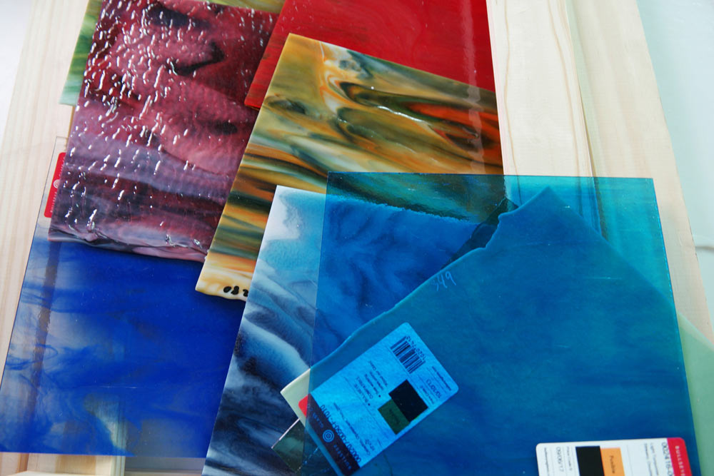 Variety of colourful handmade glass sheets displaying different textures and patterns from disability workshop