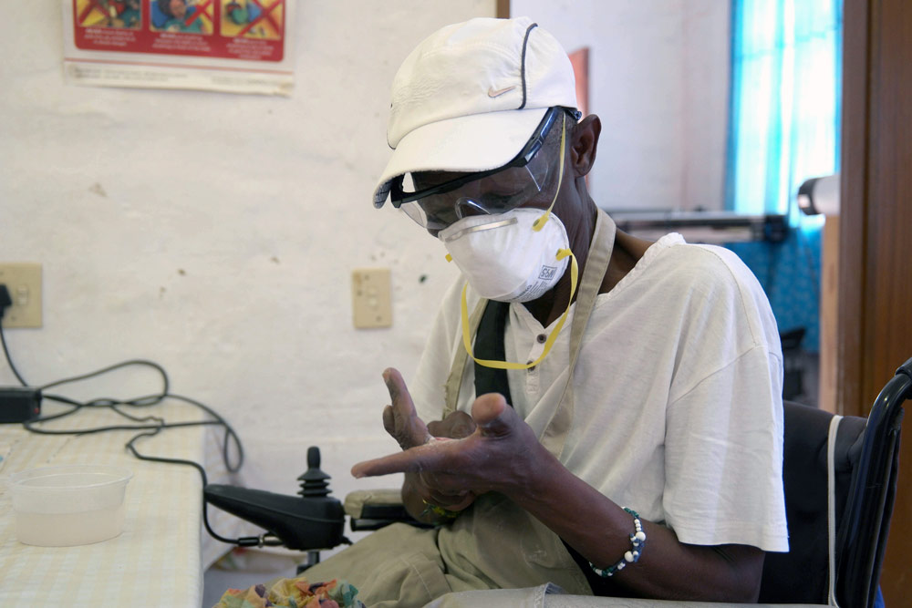 Workshop participant wearing protective safety gear including respirator mask and safety glasses during glass work training